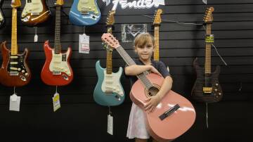 Alexis Lean clutches her first guitar at the Musos Corner May the Fourth sale on Saturday. Pink is her favourite colour, she said, and she has been learning to play with her dad. Picture by Marina Neil